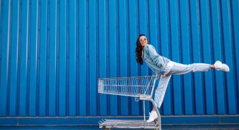 Kobieta z wózkiem sklepowym na niebieskim tle
